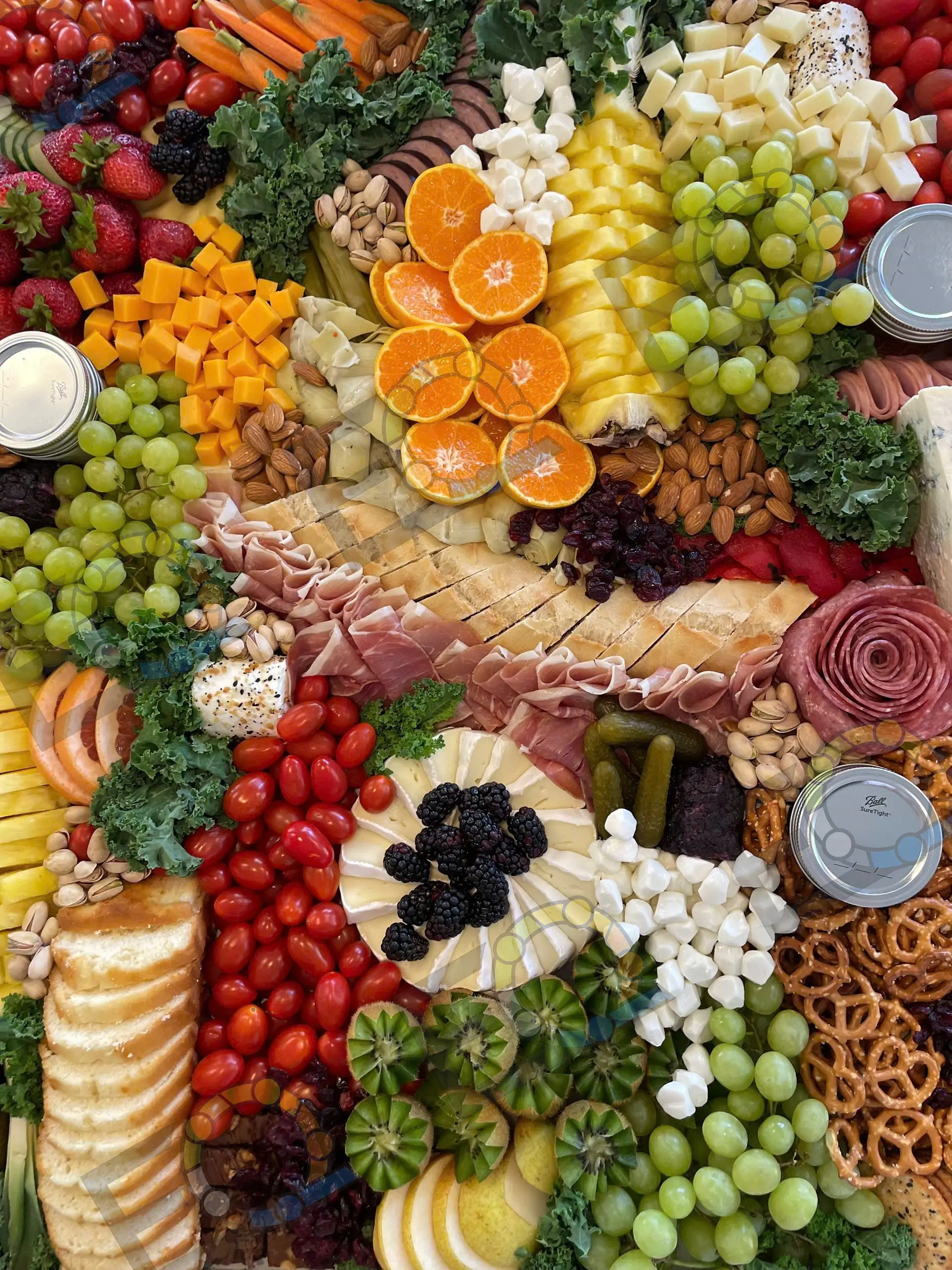 Close detail of a charcuterie board with citrus, grapes, olives and cured meats