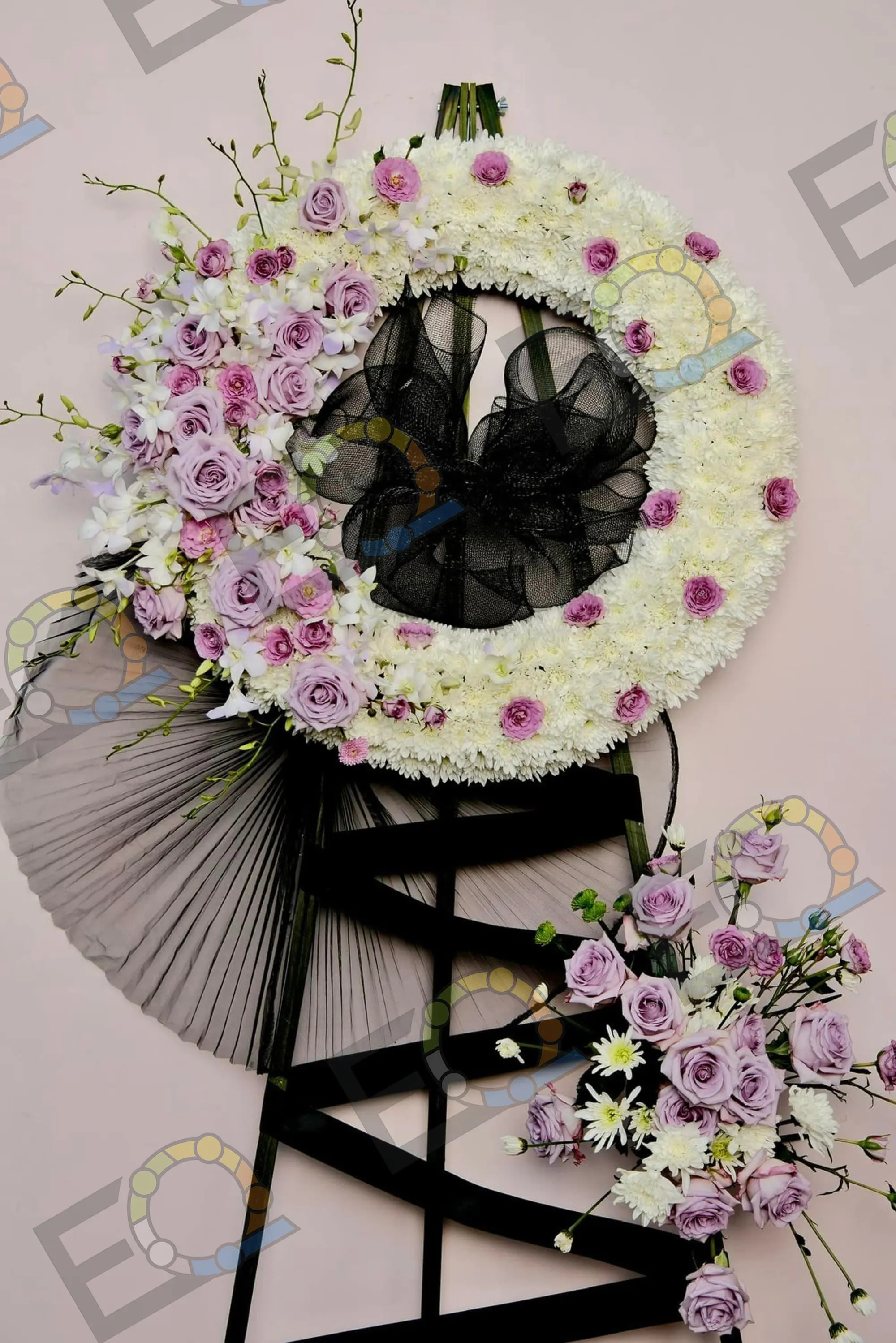 A standing memorial wreath of white and lavender blooms